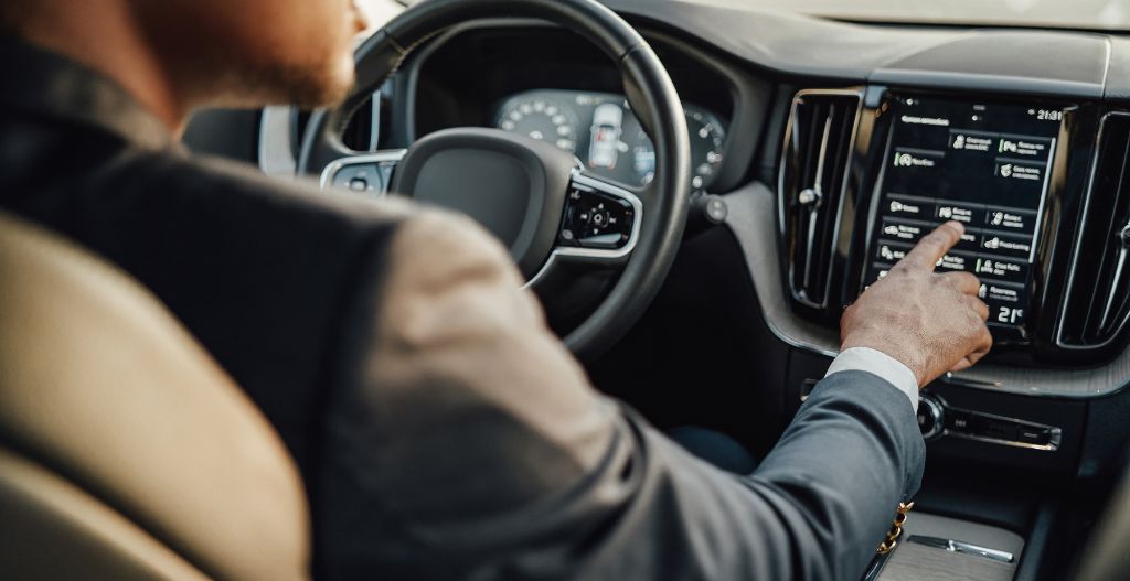 A man in a suit using a touch screen in a car