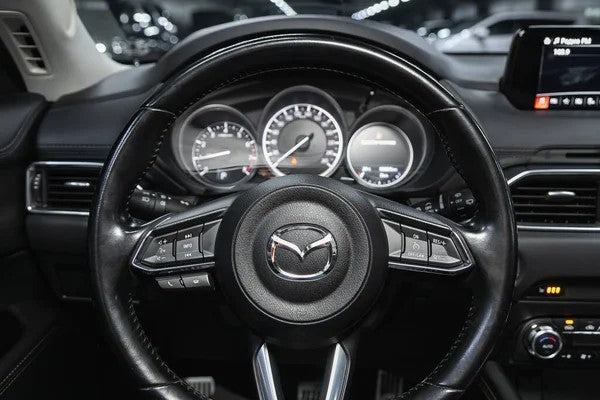 A point of view of the driver seat seeing the Mazda steering wheel