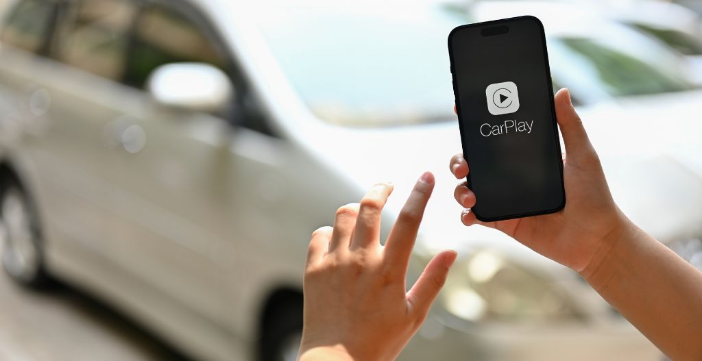 person holding a smartphone with the CarPlay app displayed on the screen